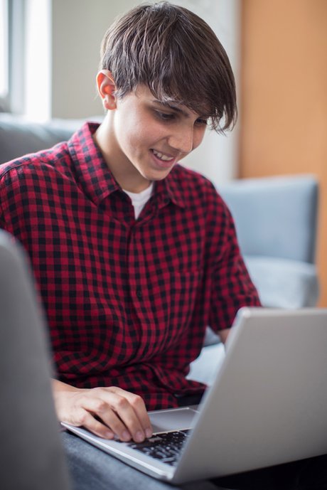 Teenage Boy Working On Laptop At Home